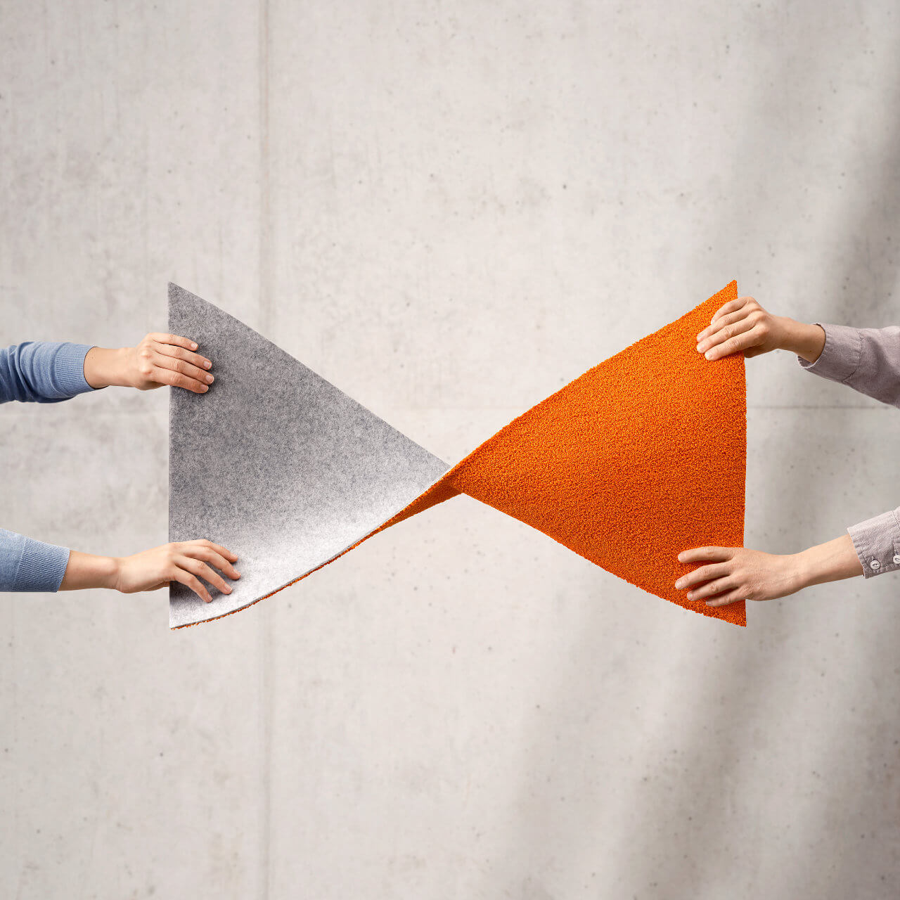 Two pairs of hands holding a piece of carpet in a twisted curve to symbolize a lemniscate and eternal use.