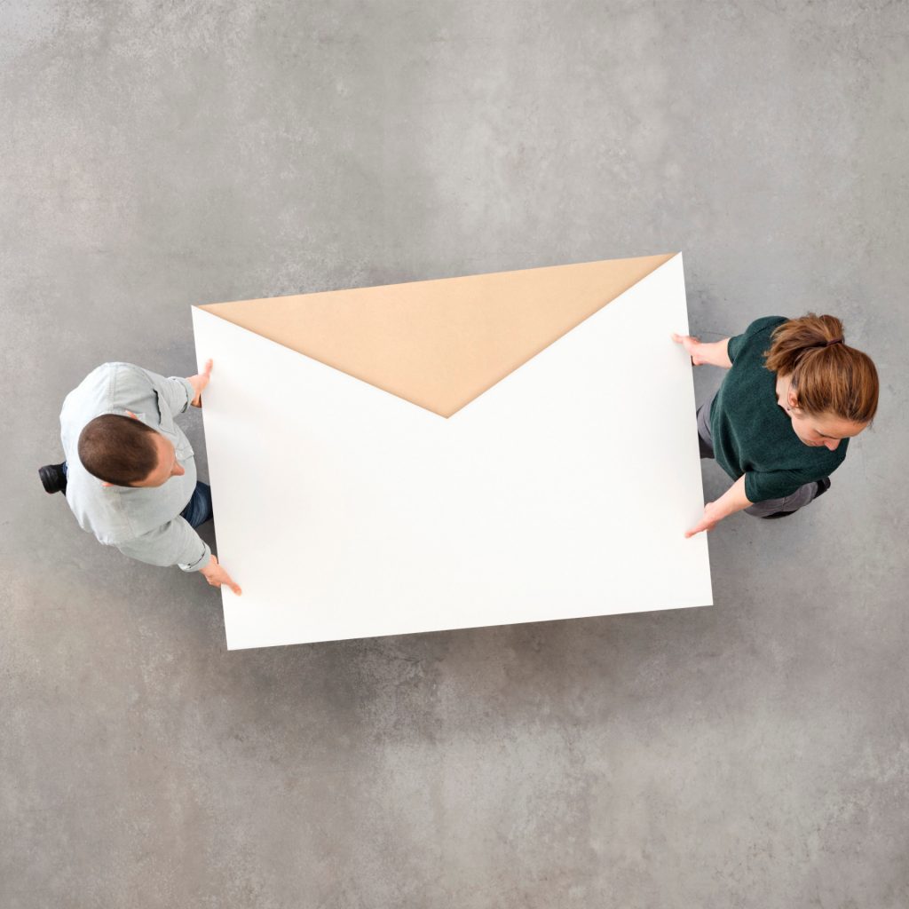 Two people carrying a giant envelope, symbolizing return.