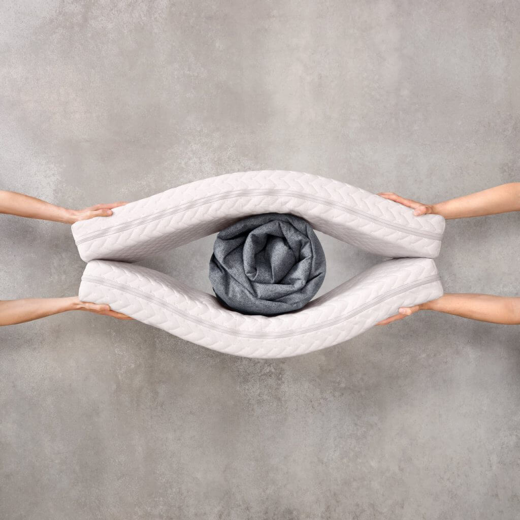 Two pairs of hands holding two baby mattresses together to shape an eye, symbolizing material transparency.