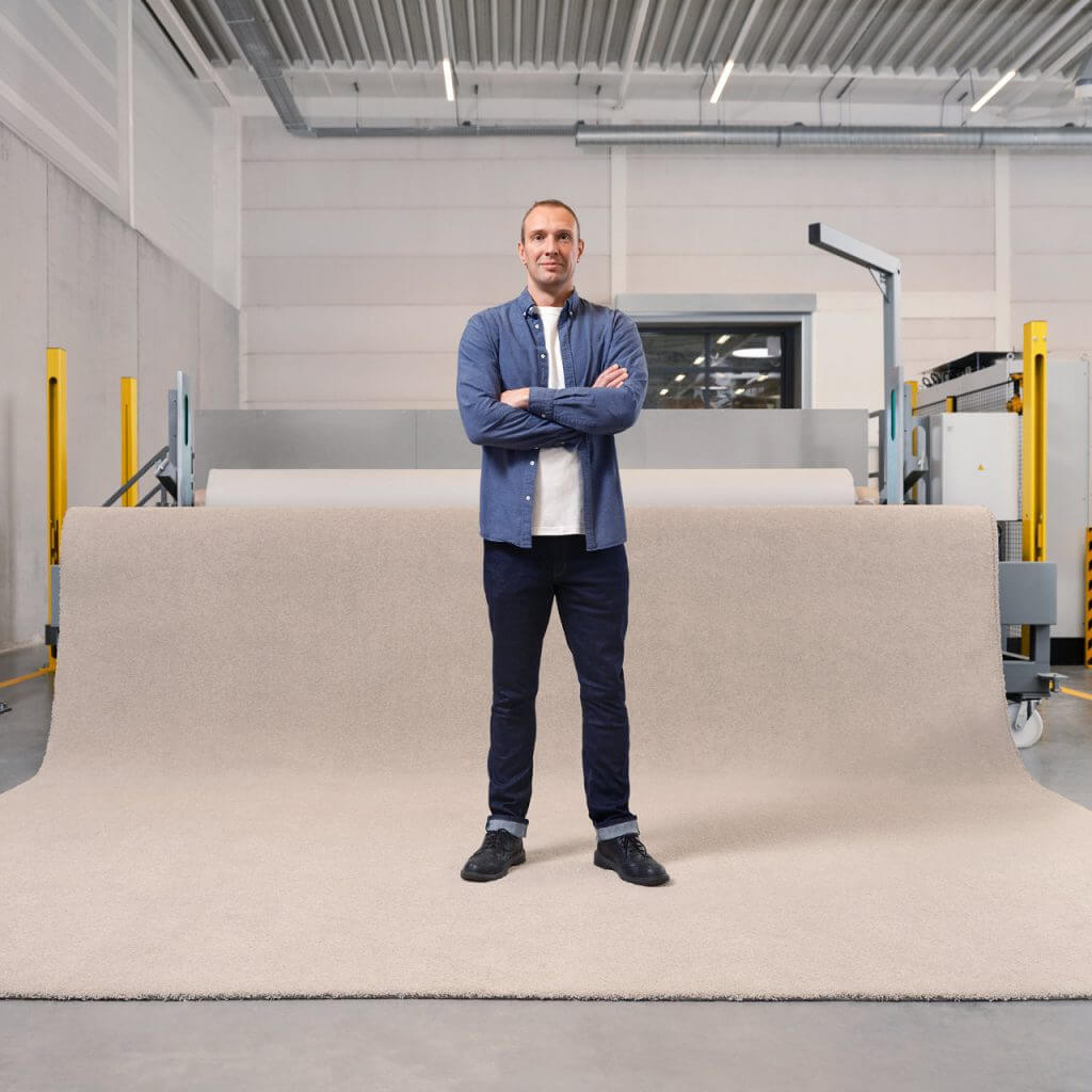 Man in blue standing on a rolled out mono-poyester carpet role.